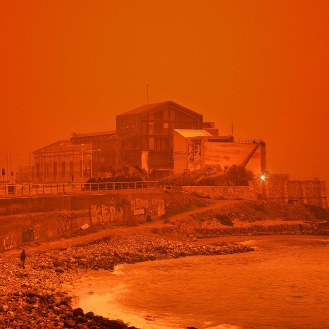 Muž kráča po pláži počas piesočnej búrky na Kréte.