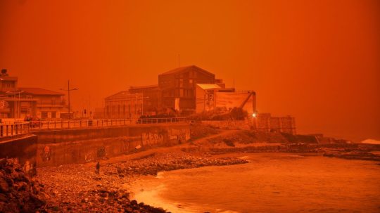 Muž kráča po pláži počas piesočnej búrky na Kréte.