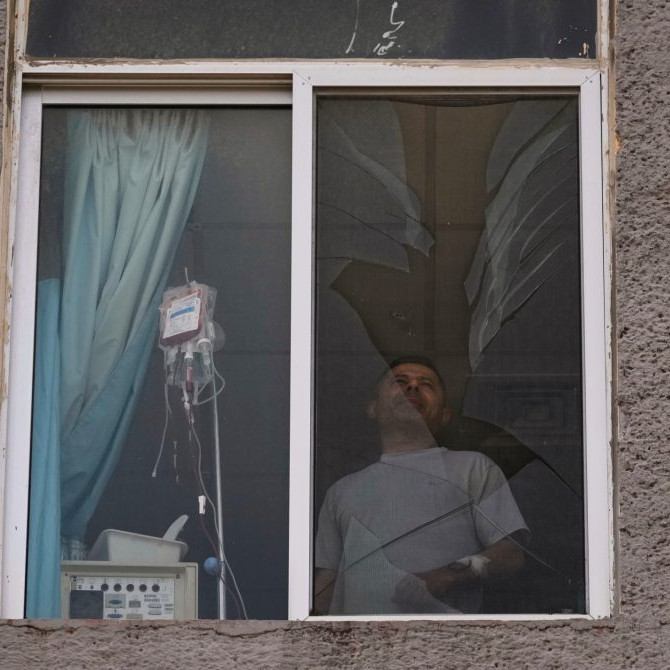 Pacient nemocnice stojí pred rozbitým oknom v Libanone po izraelskom útoku.
