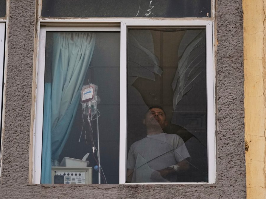 Pacient nemocnice stojí pred rozbitým oknom v Libanone po izraelskom útoku.