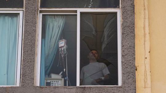 Pacient nemocnice stojí pred rozbitým oknom v Libanone po izraelskom útoku.