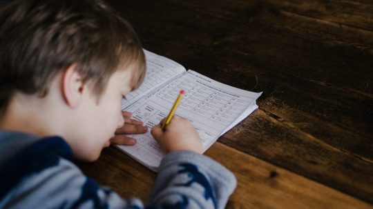 Na snímke si dieťa robí domáce úlohy.