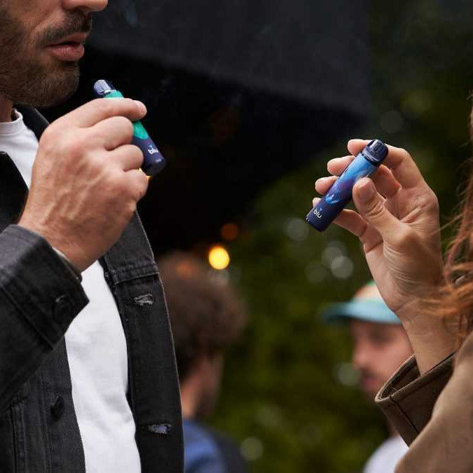 Žena a muž fajčia vape na verejnosti.
