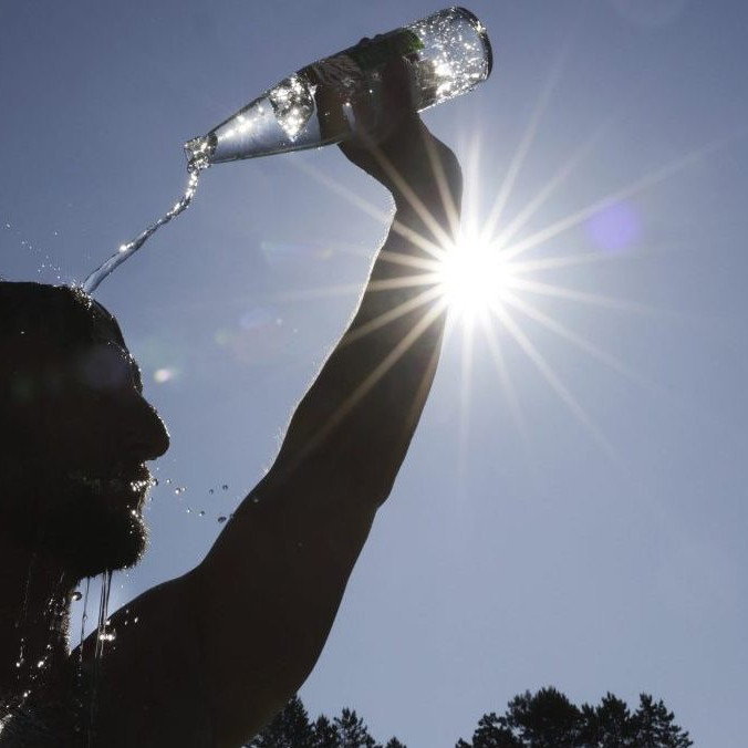 Na ilustračnej snímke sa muž olieva vodou počas horúčavy.