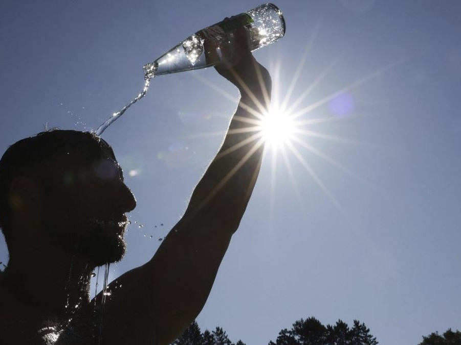 Na ilustračnej snímke sa muž olieva vodou počas horúčavy.