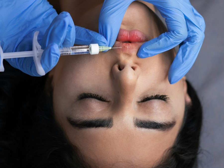 Na snímke pichá lekár žene do pier ihlu.