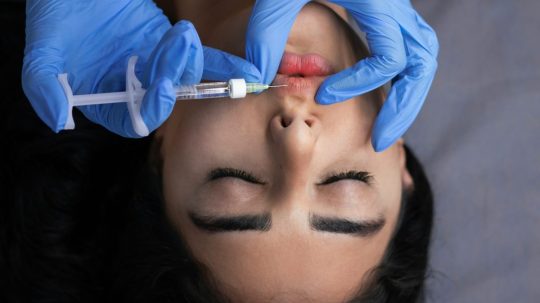 Na snímke pichá lekár žene do pier ihlu.