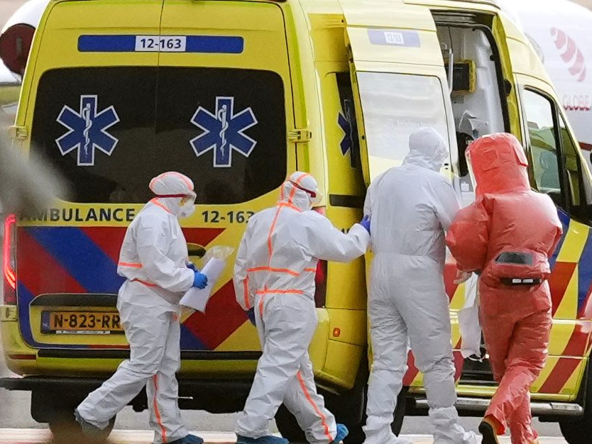 Na snímke zdravotnícky personál pomáha pacientovi nasadnúť do sanitky.