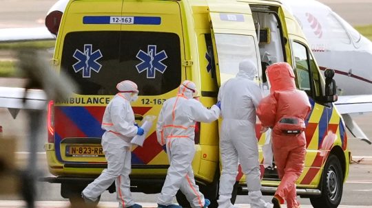 Na snímke zdravotnícky personál pomáha pacientovi nasadnúť do sanitky.