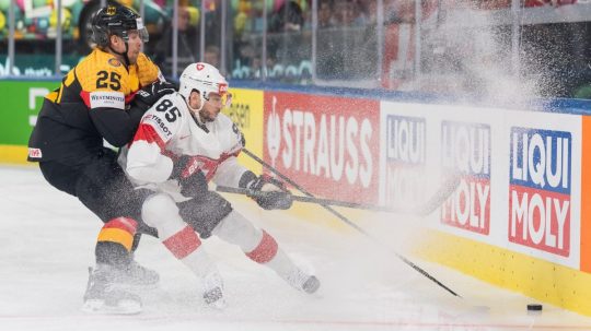 Hokejista Švajčiarska Sven Andrighetto a hráč Nemecka Leon Huttl bojujú o puk.