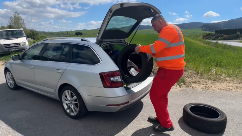 Na snímke muž vkladá do auto pneumatiky.