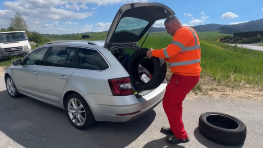 Na snímke muž vkladá do auto pneumatiky.