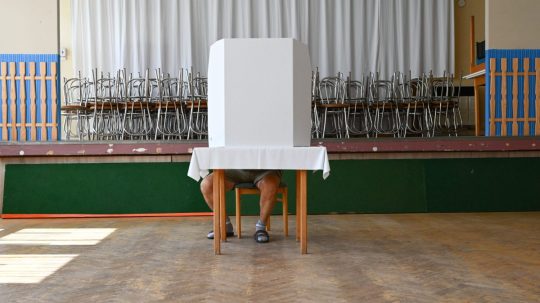 Volič upravuje hlasovací lístok za volebnou zástenou.