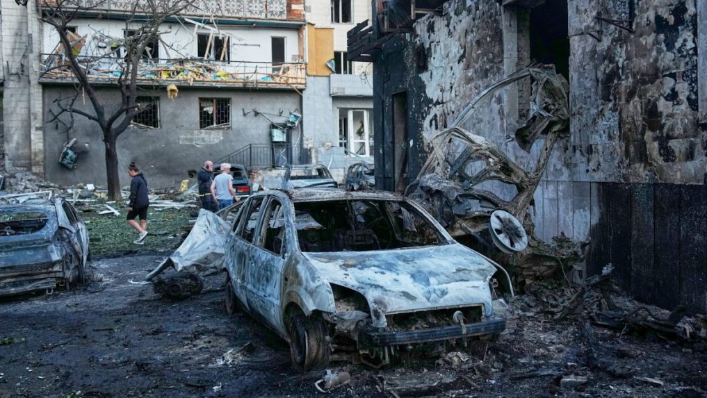 Ľudia kráčajú medzi troskami bytovky po ruskom raketovom útoku v Kyjeve.