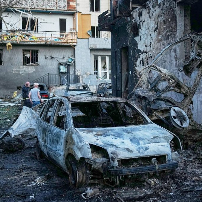 Ľudia kráčajú medzi troskami bytovky po ruskom raketovom útoku v Kyjeve.