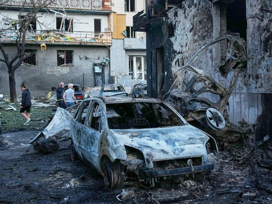 Ľudia kráčajú medzi troskami bytovky po ruskom raketovom útoku v Kyjeve.