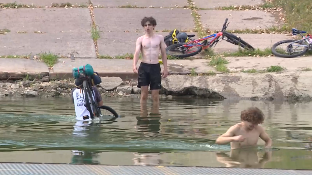 Cyklisti sa brodia cez rieku.
