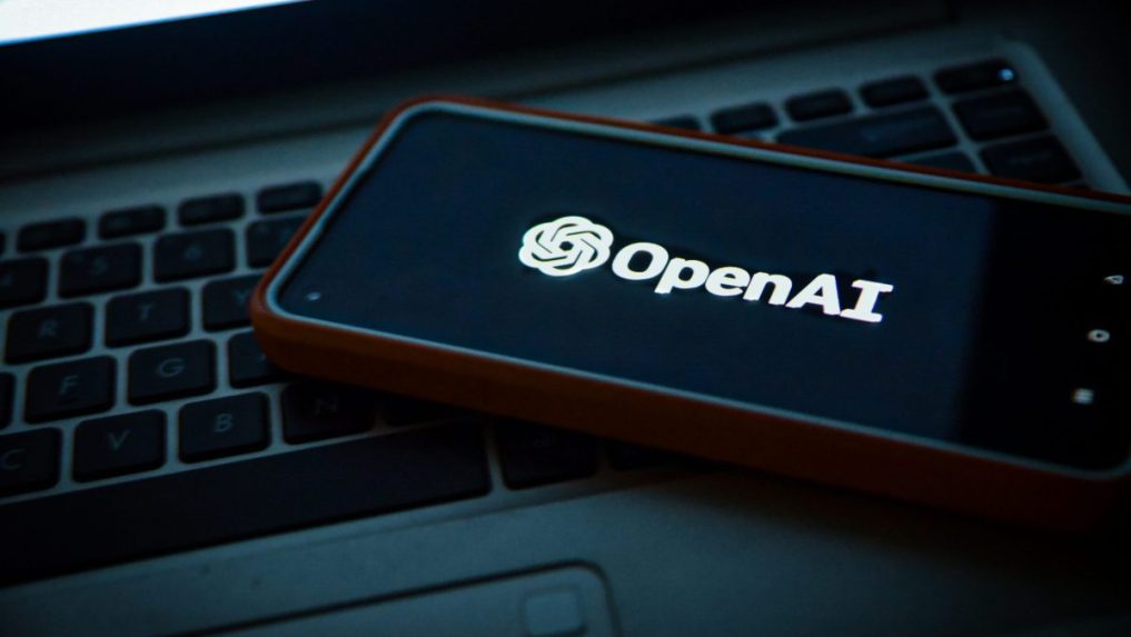 Na snímke telefón s logom OpenAI položený na notebooku.