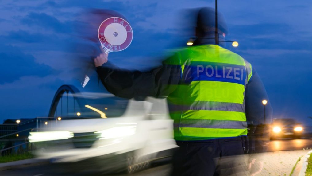 Policajt zastavuje vodiča osobného auta počas kontroly na nemecko-poľských hraniciach.