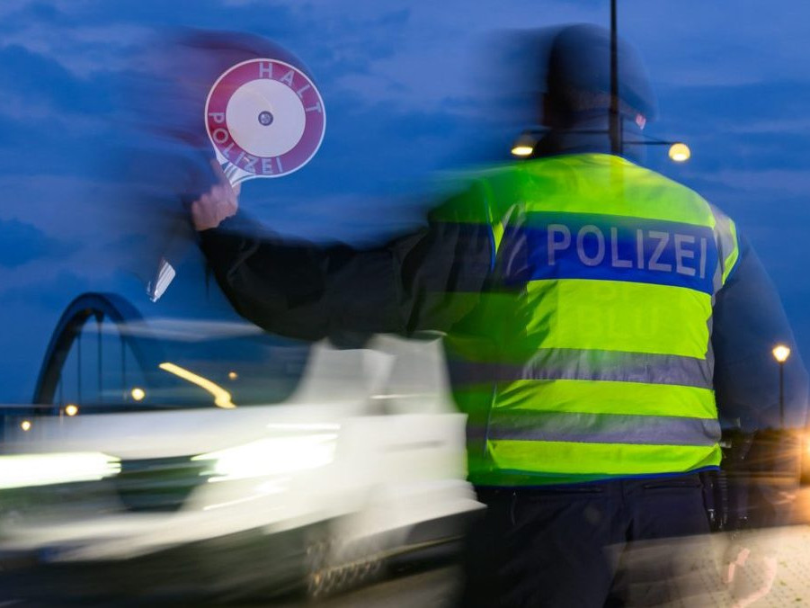 Policajt zastavuje vodiča osobného auta počas kontroly na nemecko-poľských hraniciach.