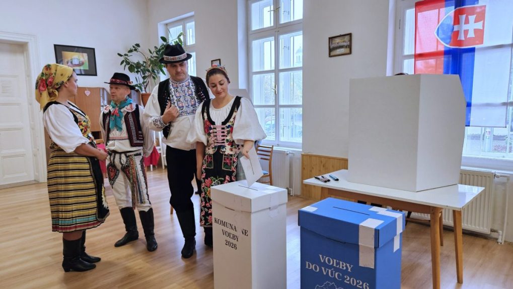 Volička z folkl&oacute;rneho s&uacute;boru Slovensk&iacute; rebeli vhadzuje v Kom&aacute;rne ob&aacute;lku s hlasovac&iacute;mi l&iacute;stkami.