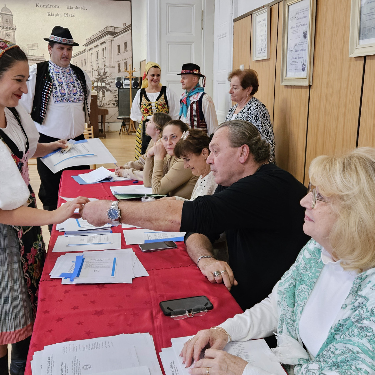 Volička z folklórneho súboru Slovenskí rebeli si preberá hlasovacie lístky v Komárne.