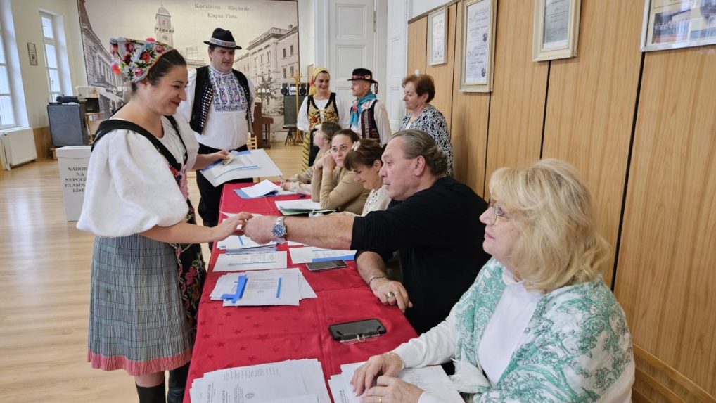 Volička z folkl&oacute;rneho s&uacute;boru Slovensk&iacute; rebeli si preber&aacute; hlasovacie l&iacute;stky v Kom&aacute;rne.