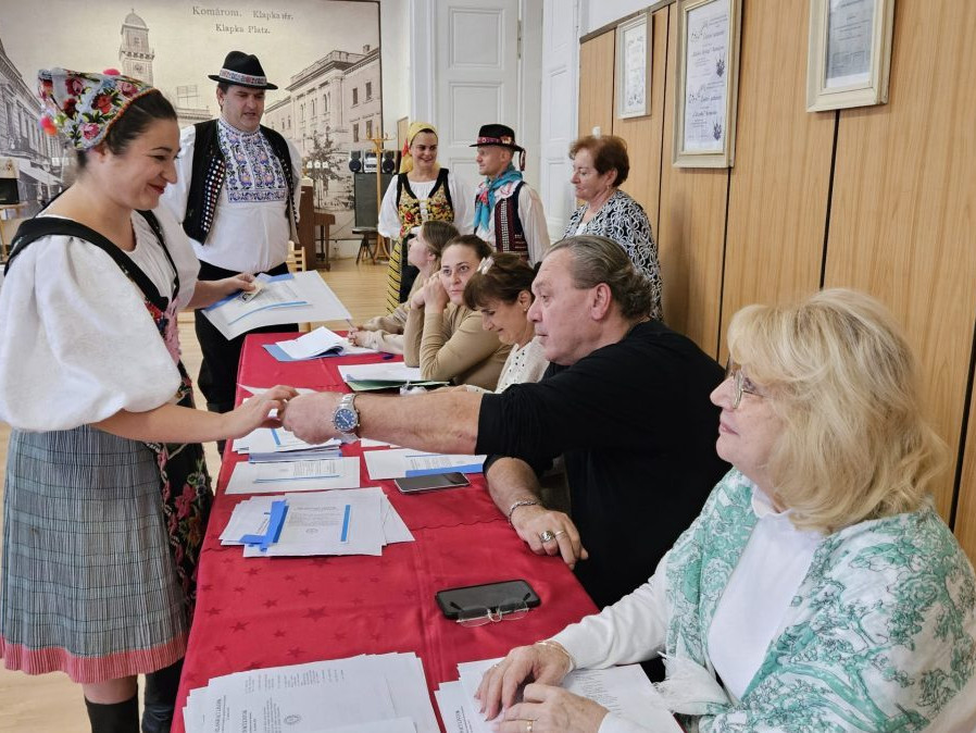 Volička z folklórneho súboru Slovenskí rebeli si preberá hlasovacie lístky v Komárne.