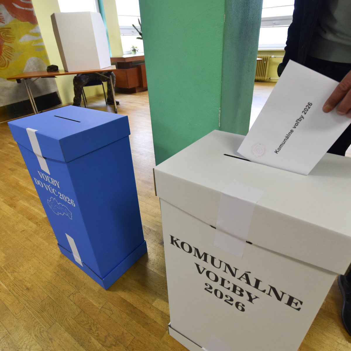 Volič vhadzuje obálku s hlasovacími lístkami do volebnej schránky.