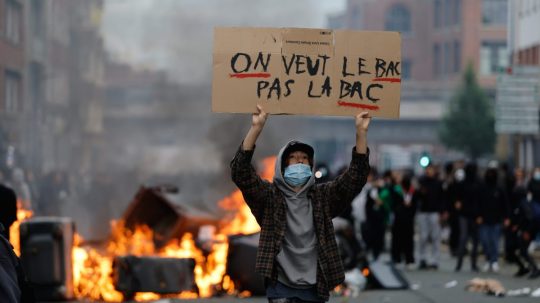 Študent s transparentom na proteste.