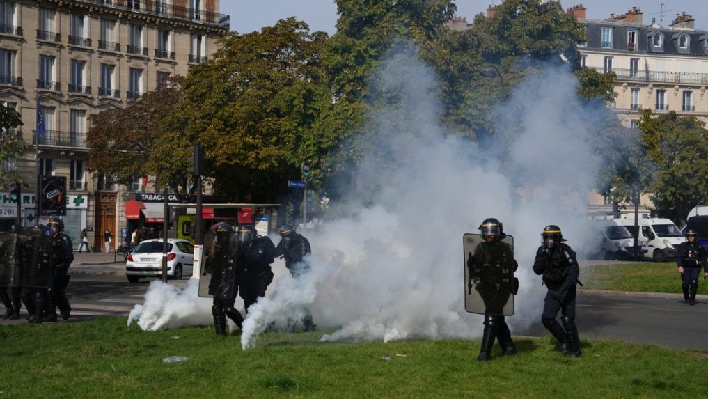 Policajti prechádzajú cez slzný plyn