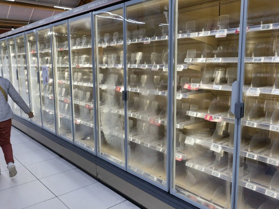 Žena prechádza okolo prázdnych chladničiek v supermarkete.