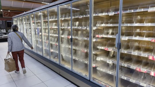Žena prechádza okolo prázdnych chladničiek v supermarkete.